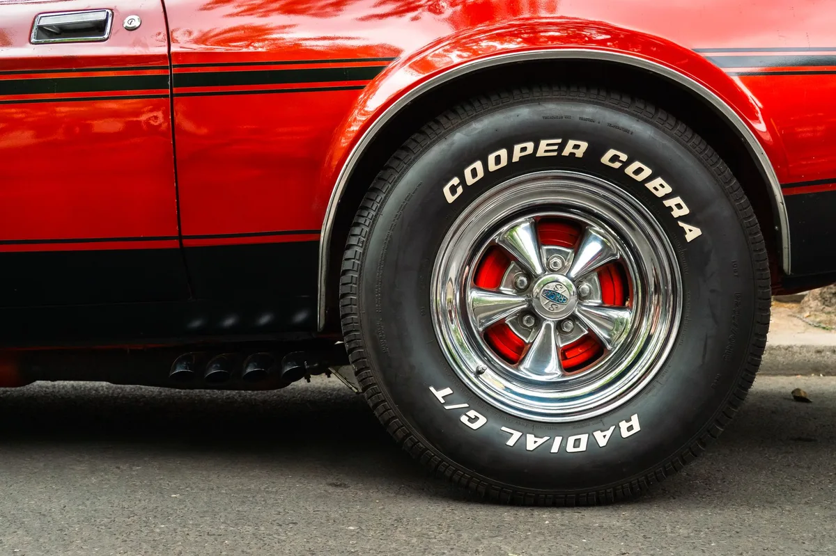 Roda de carro com pneu em close, mostrando detalhes da roda de liga leve