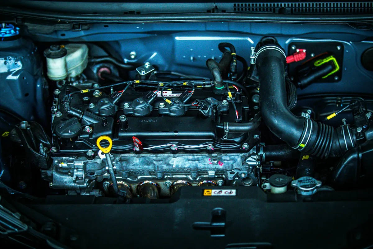 Motor de carro em close dentro do cofre, com peças aparentes.