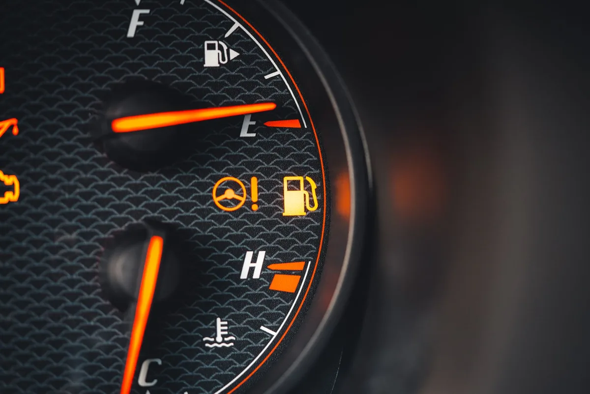 Painel de instrumentos de carro em close mostrando medidores de combustível e velocidade