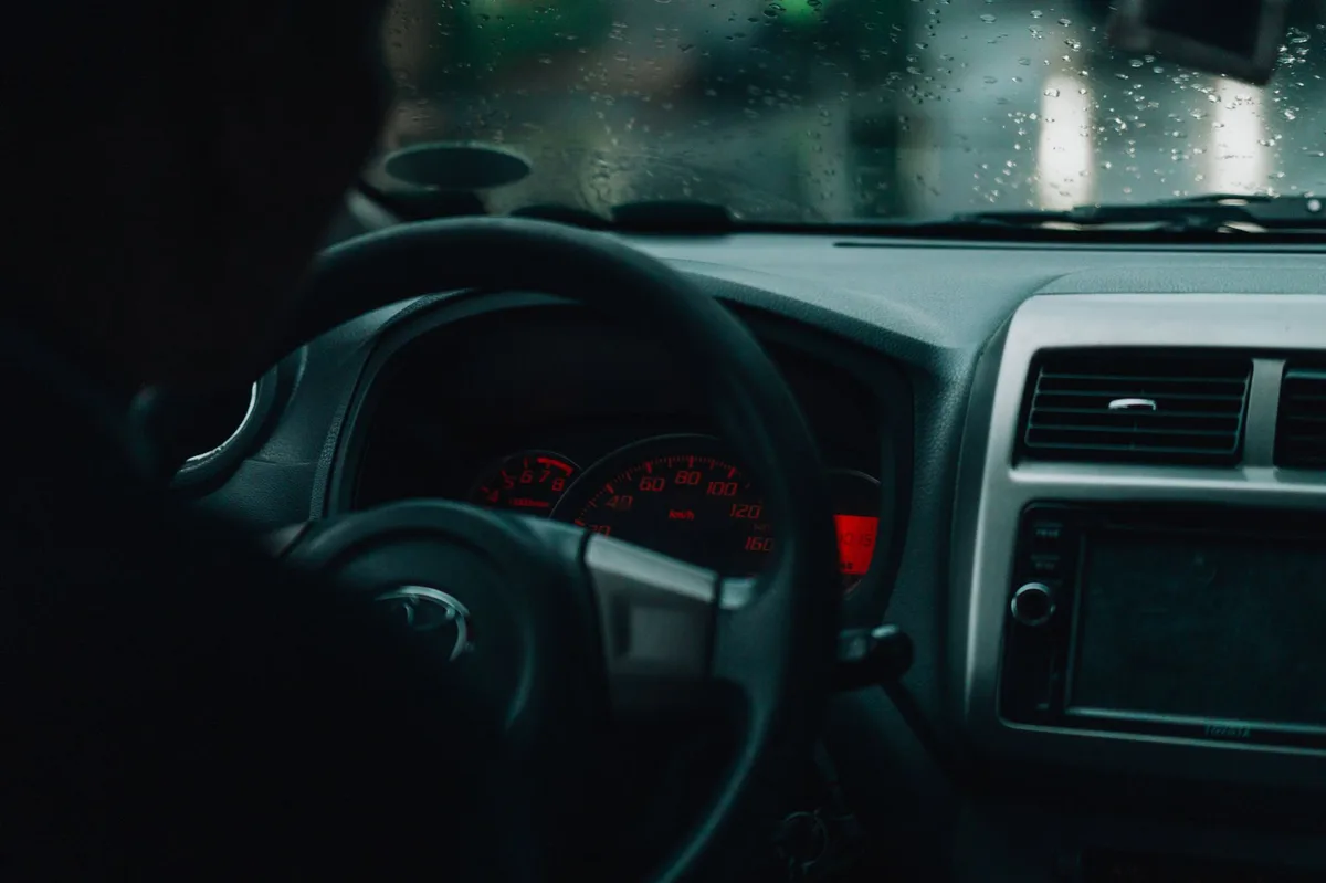 Painel de carro e volante vistos do banco do motorista, mostrando instrumentos e para-brisa