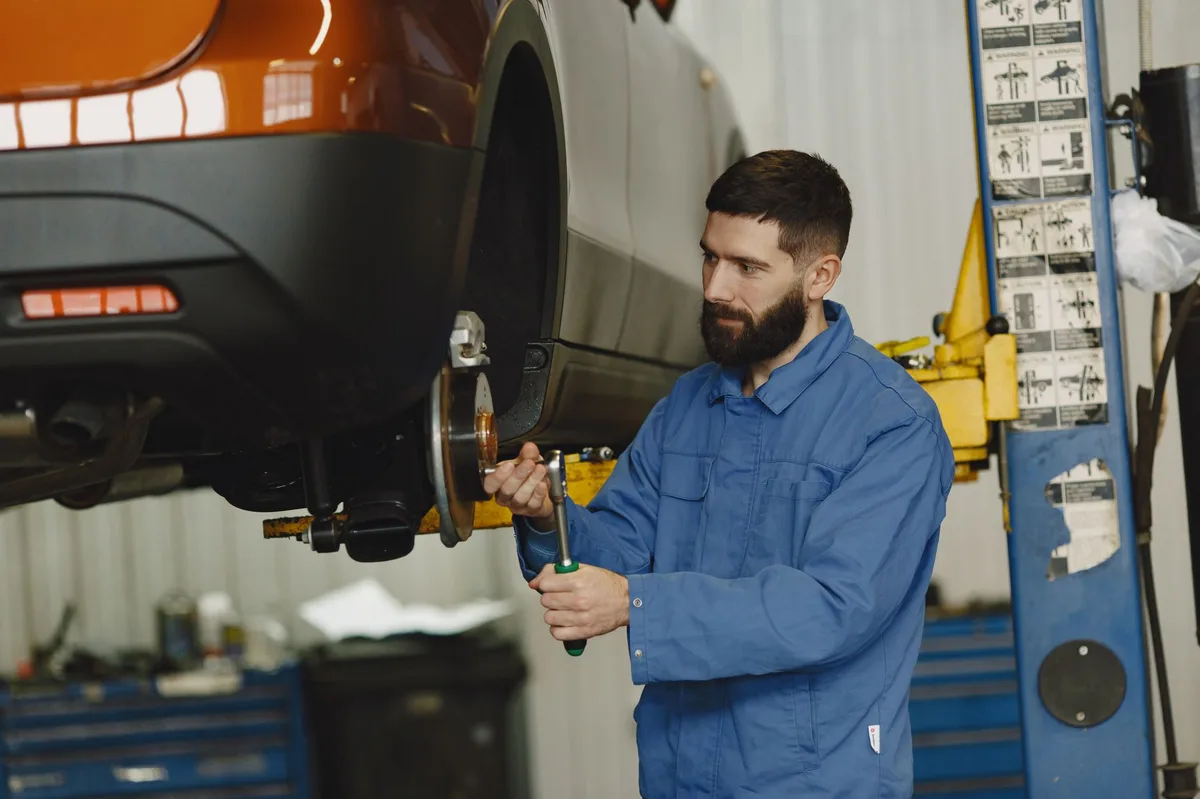 Mecânico trabalhando sob um carro elevado em oficina automotiva