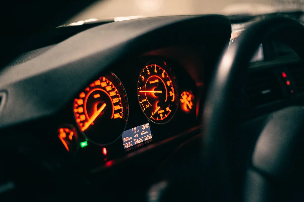 Painel de instrumentos de carro iluminado mostrando velocímetro e indicadores