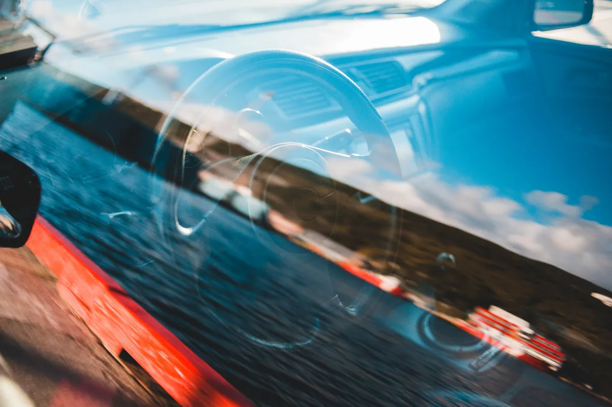 Interior de carro moderno mostrando painel e volante, com visão dos vidros