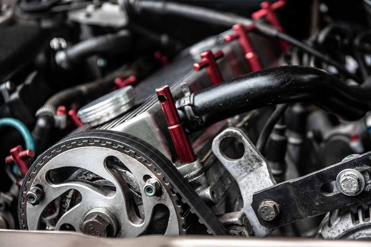 Motor de carro em close mostrando componentes internos e correias